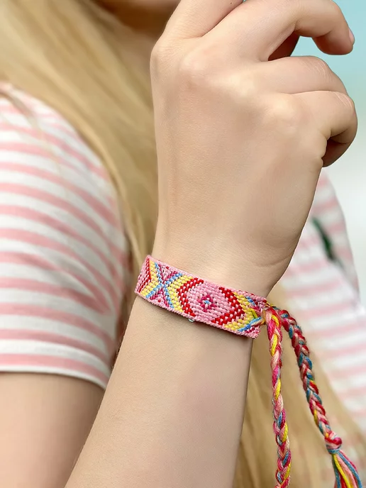 девушка плетет браслет из ниток на закате